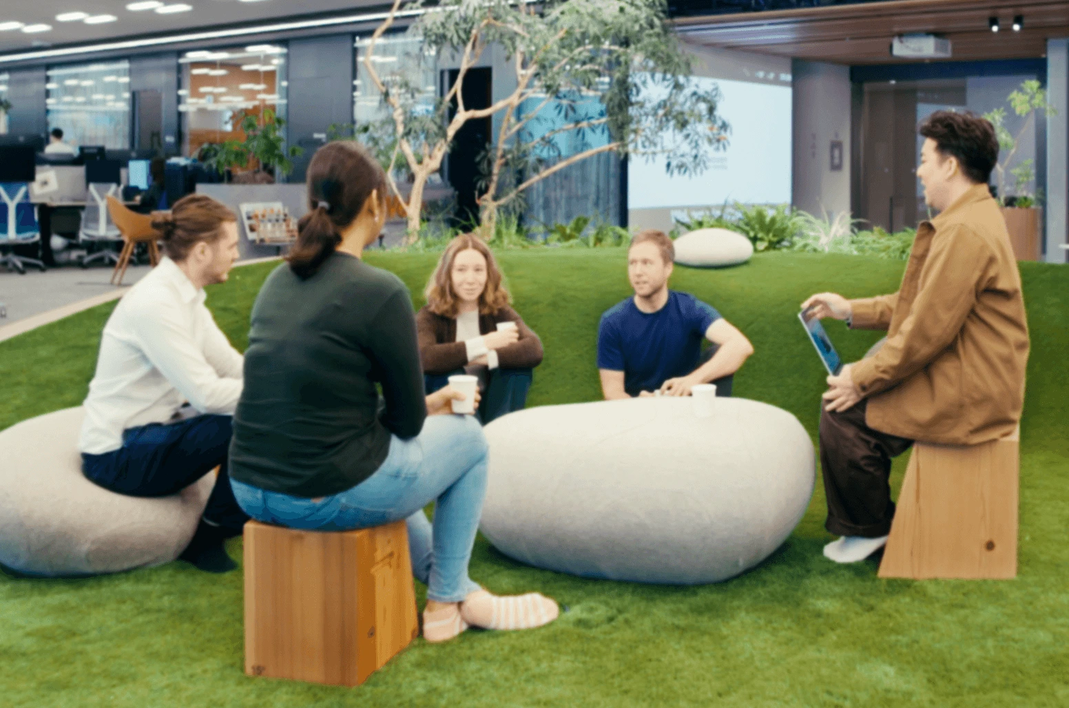 Employees collaborating on in-door astroturf in casual team discussion