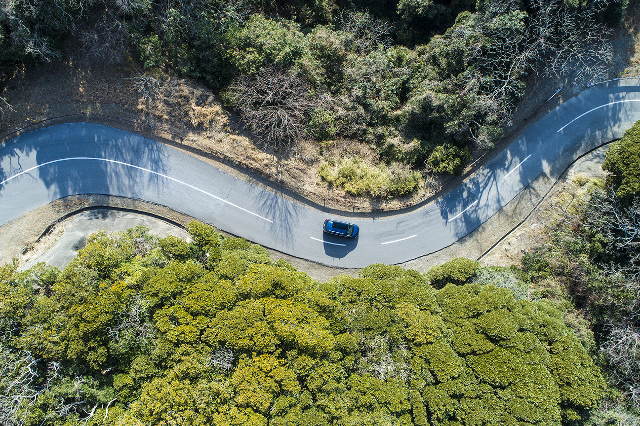 自然の中の曲がりくねった道路を走行する車両の俯瞰図